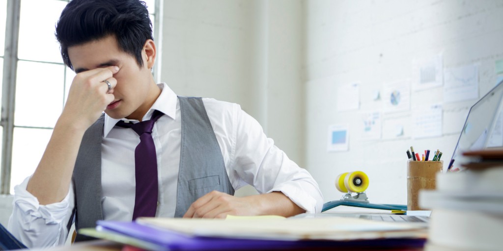 Stressed young man sitting at office desk