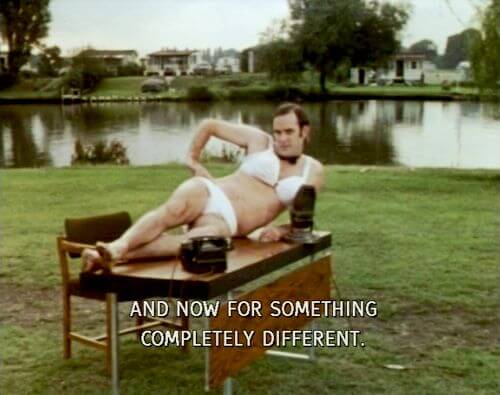 Jon Cleese laying on a table outside wearing a bra